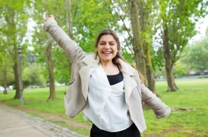 Mujer sonriente en parque reflejando bienestar y sistema inmune fortalecido