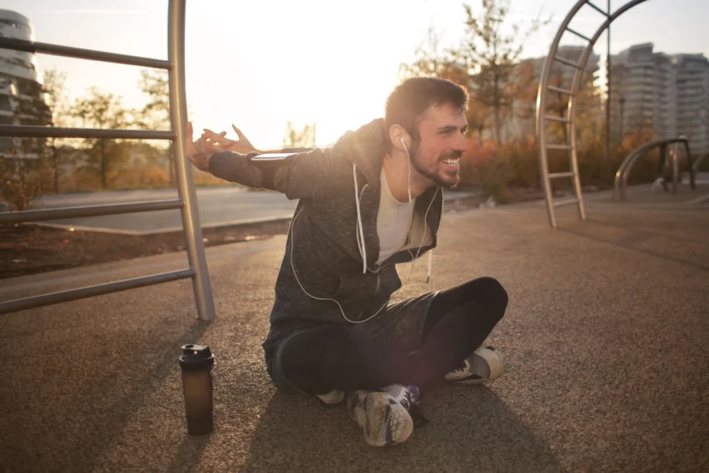 Hombre realizando estiramientos después de hacer ejercicio, representando bienestar muscular y hábitos saludables.