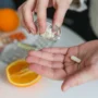 Persona tomando una cápsula de suplemento nutricional junto a naranjas y diferentes vitaminas